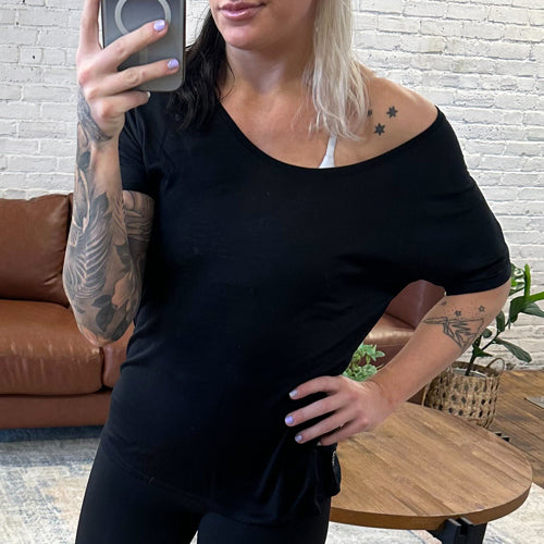 Model wearing a black slouchy tee, that falls off the shoulder.