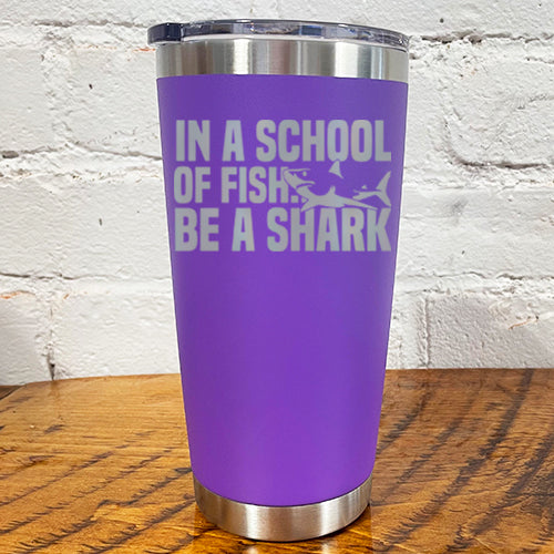 20oz purple tumbler with silver saying "in a school of fish be a shark" with a shark cartoon over the word "fish"