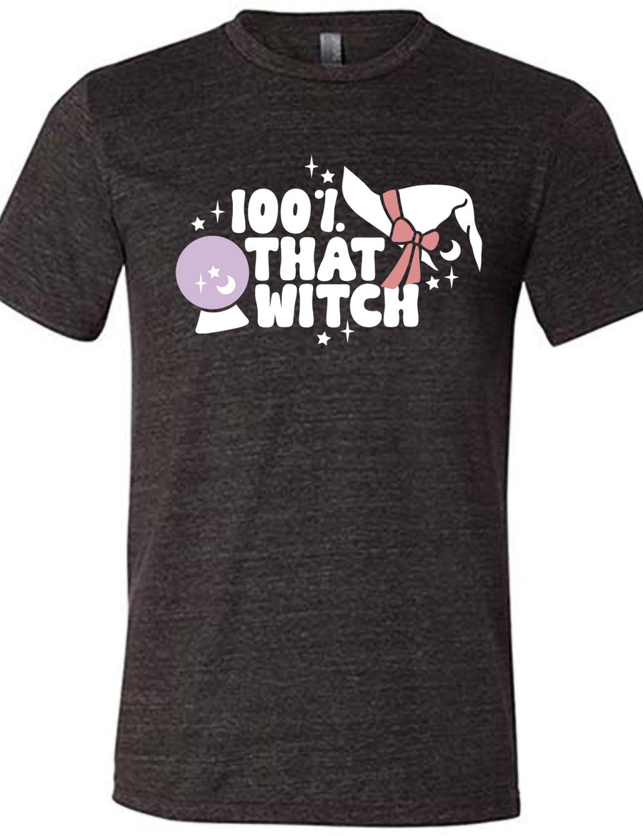 black unisex tee with the words "100% that witch" next to the graphic of a witch hat with a bow, a crystal ball, and some stars