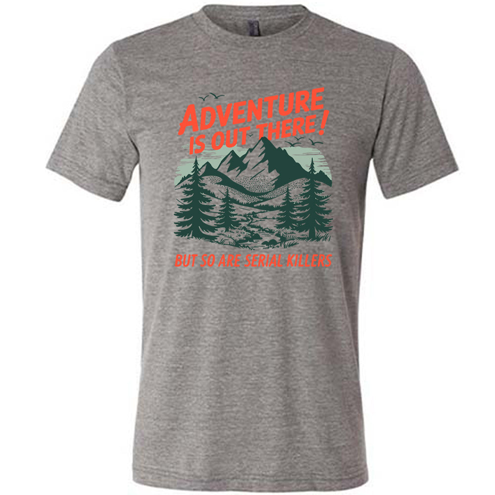 grey unisex tee with the words "adventure is out there! but so are serial killers" on it, with the graphic of mountains and woods and birds flying 