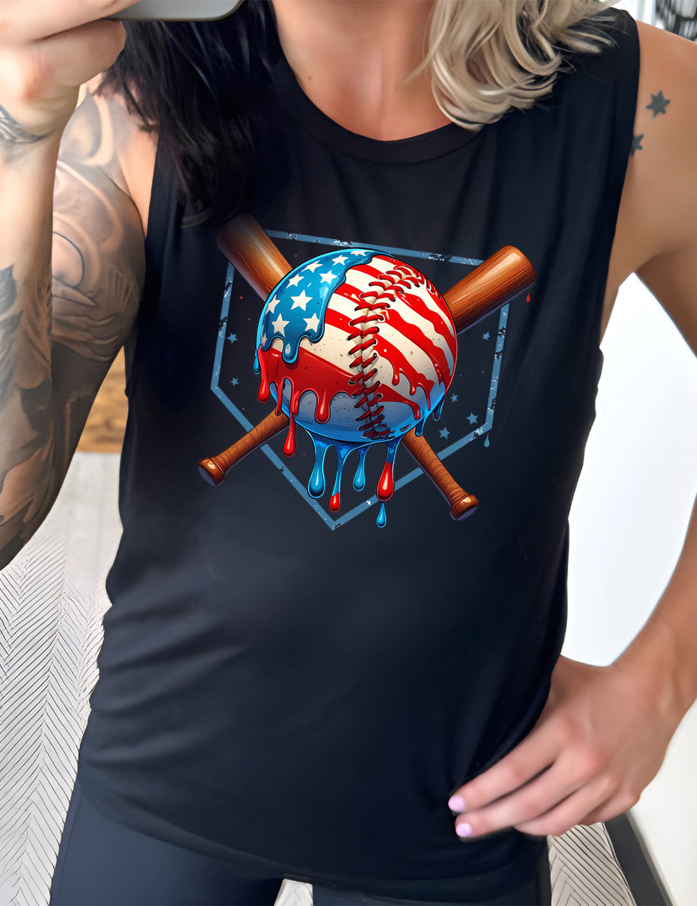 black muscle tank with the graphic of a baseball painted (and dripping) with the American flag, and two baseball bats crossed behind it, all in front of a starry baseball diamond