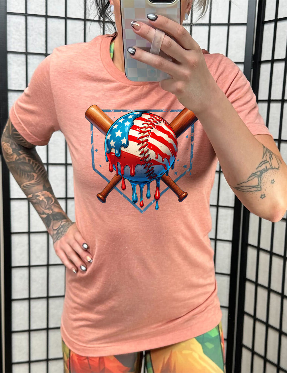 sunset unisex tee with the graphic of a baseball painted (and dripping) with the American flag, and two baseball bats crossed behind it, all in front of a starry baseball diamond