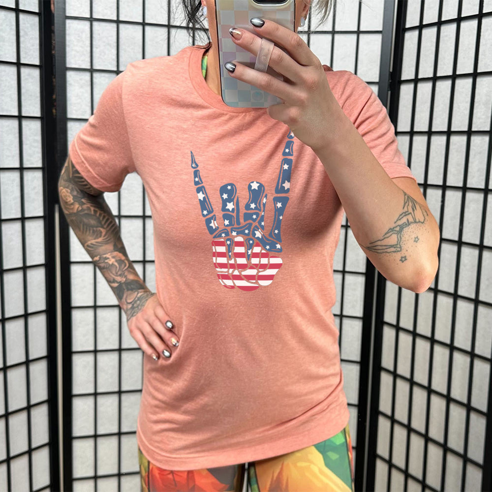 Model wearing sunset colored shirt with an American flag skeleton hand graphic on it