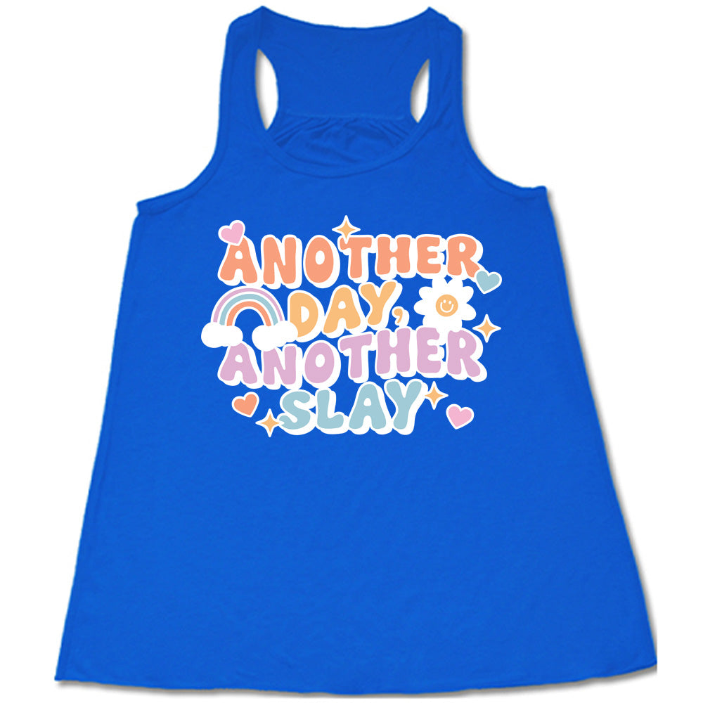blue racerback flowy tank with the words "another day, another slay" on it, with little graphics of stars, hearts, a sun, and a rainbow
