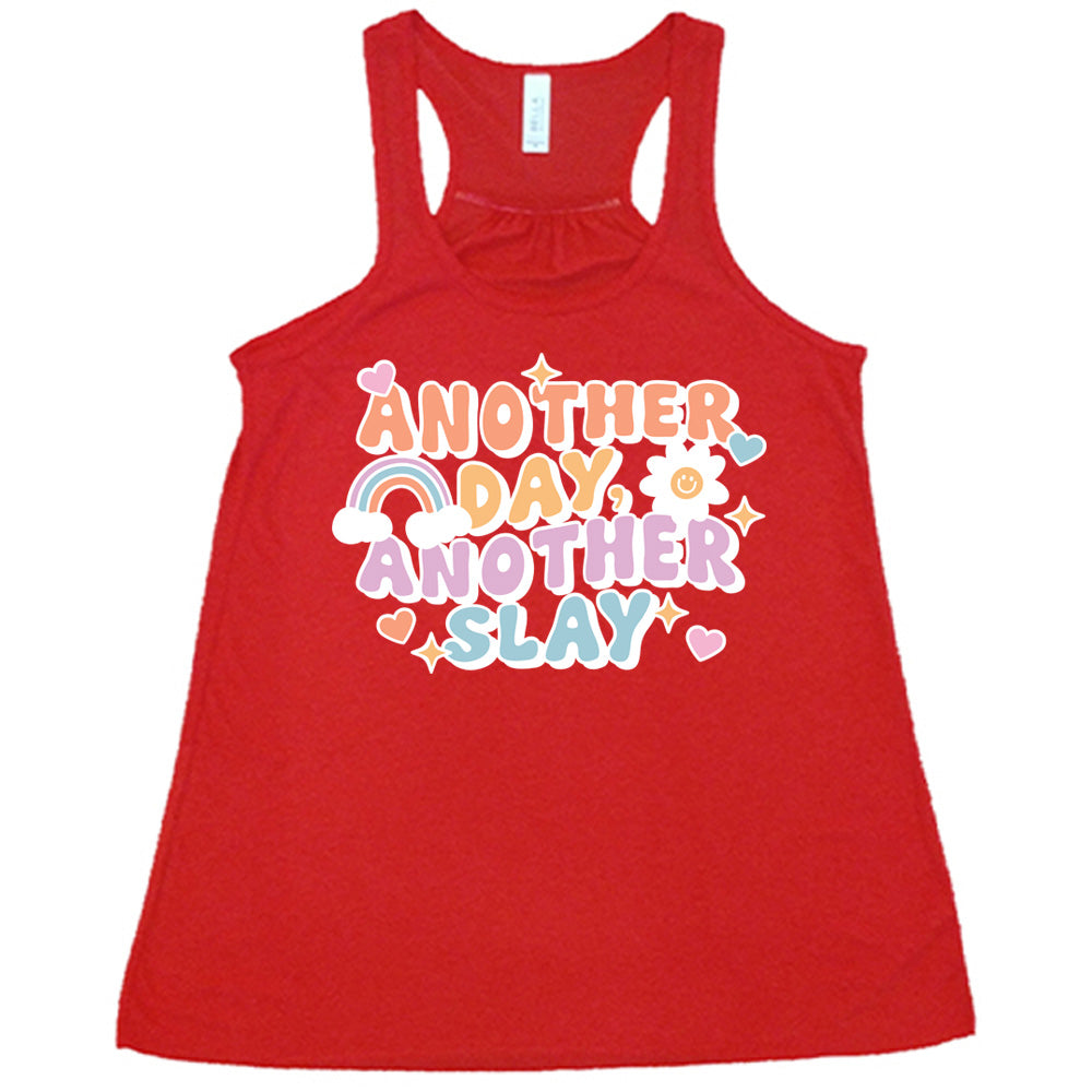 red racerback flowy tank with the words "another day, another slay" on it, with little graphics of stars, hearts, a sun, and a rainbow
