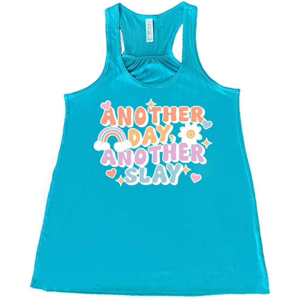 teal racerback flowy tank with the words "another day, another slay" on it, with little graphics of stars, hearts, a sun, and a rainbow
