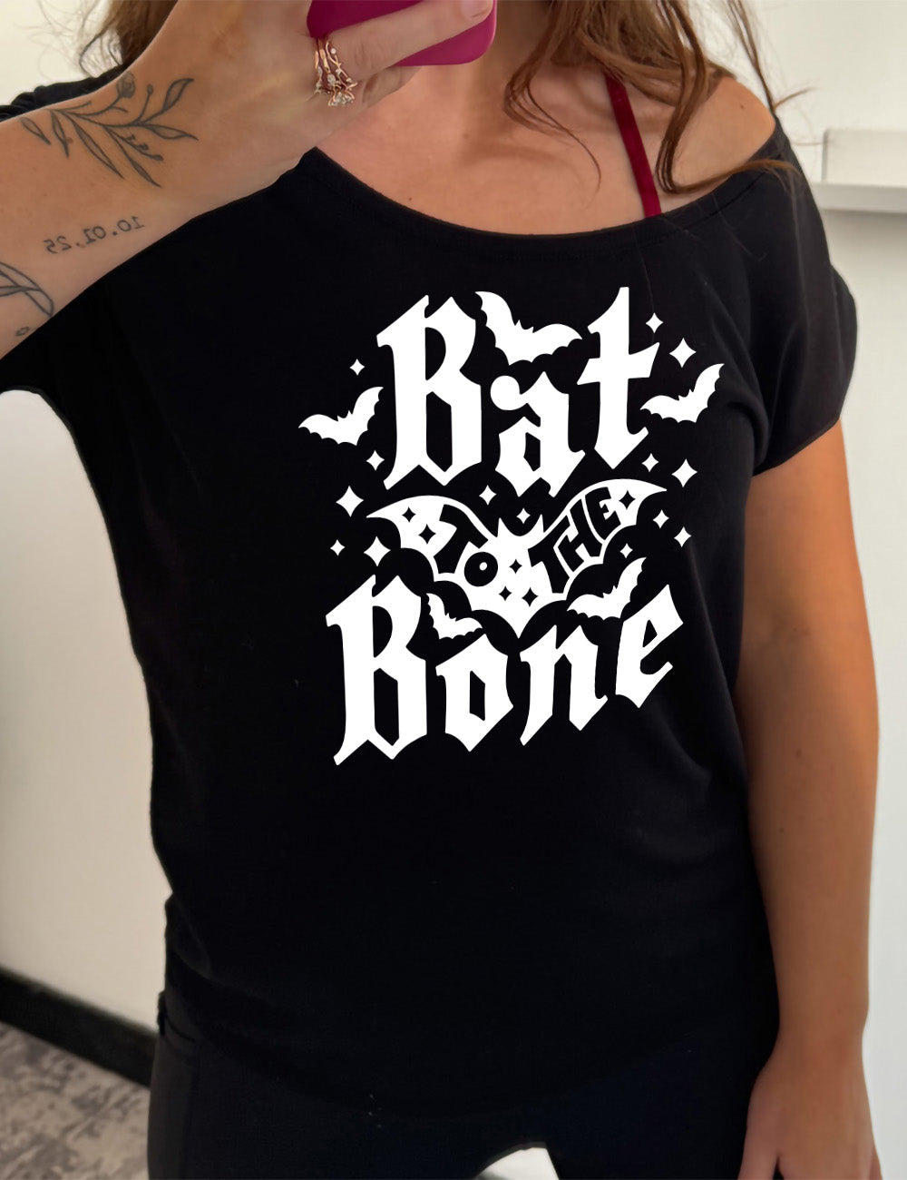 black slouchy tee with the words "bat to the bone" on it, with the words "to the" on top of a bat, and a number of other bats around the words, as well as some stars