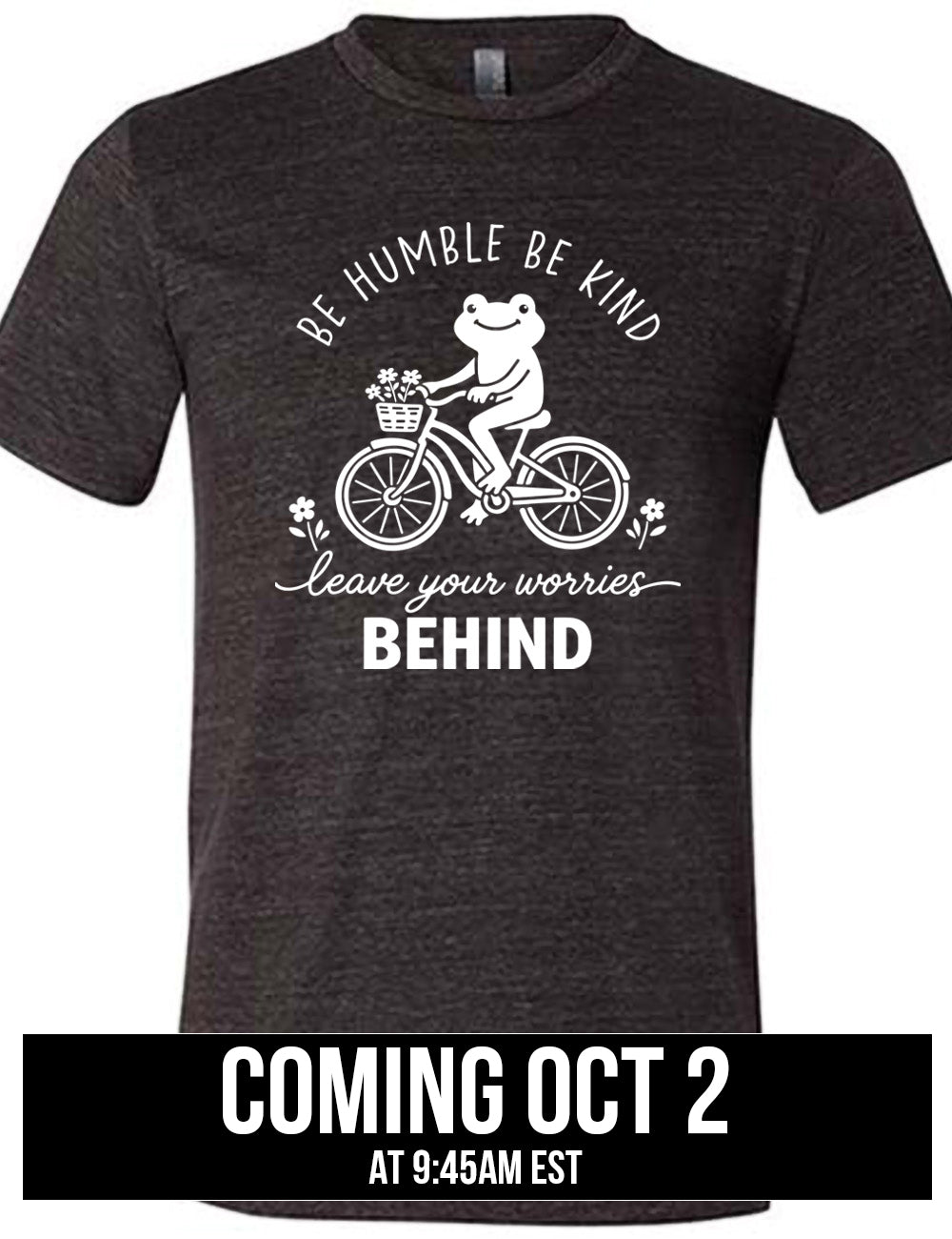 black unisex tee with the graphic of a happy frog riding a bike that has a basket of flowers attached, with a flower in front and behind the bike, and the wording arching above and ending below saying "be humble be kind leave your worries BEHIND", coming October 2nd