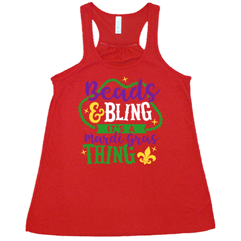 red flowy tank with the words "beads & bling it's a mardi gras thing" on it, with graphics of a ring of beads around part of the words and a few stars as well as a fleur-de-lis symbol