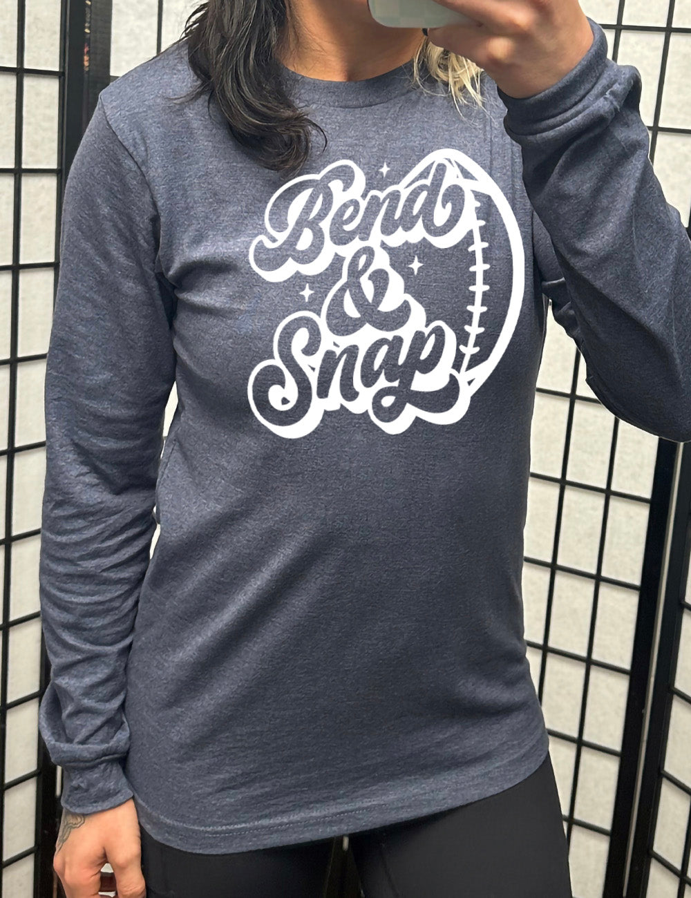 heather navy long sleeve tee with the words in cursive saying "Bend & Snap" with the outline graphic of a football slightly underneath