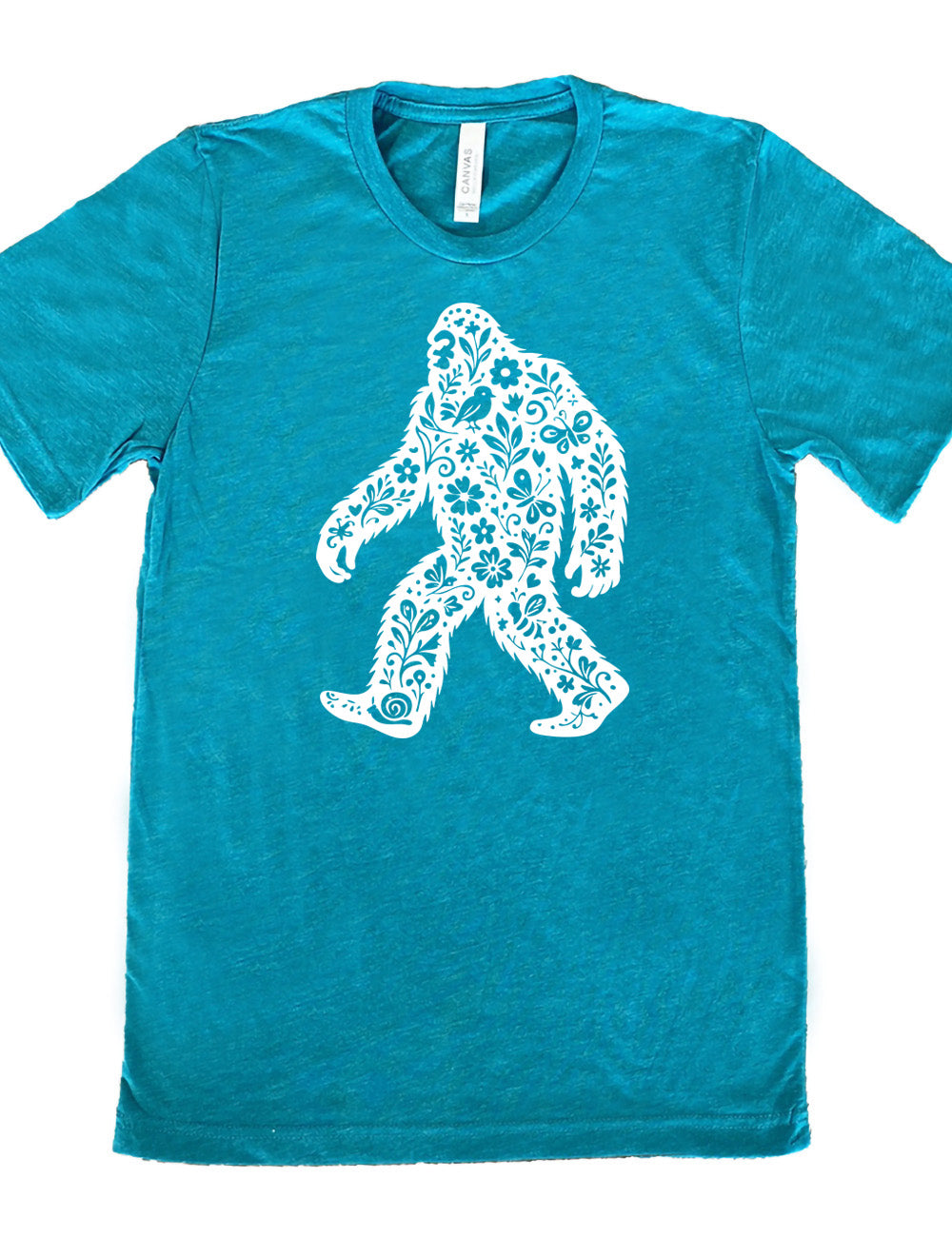 teal unisex tee with the graphic white cutout of bigfoot, which is overlayed with black flowers, plants, birds, bees, snails, and butterflies