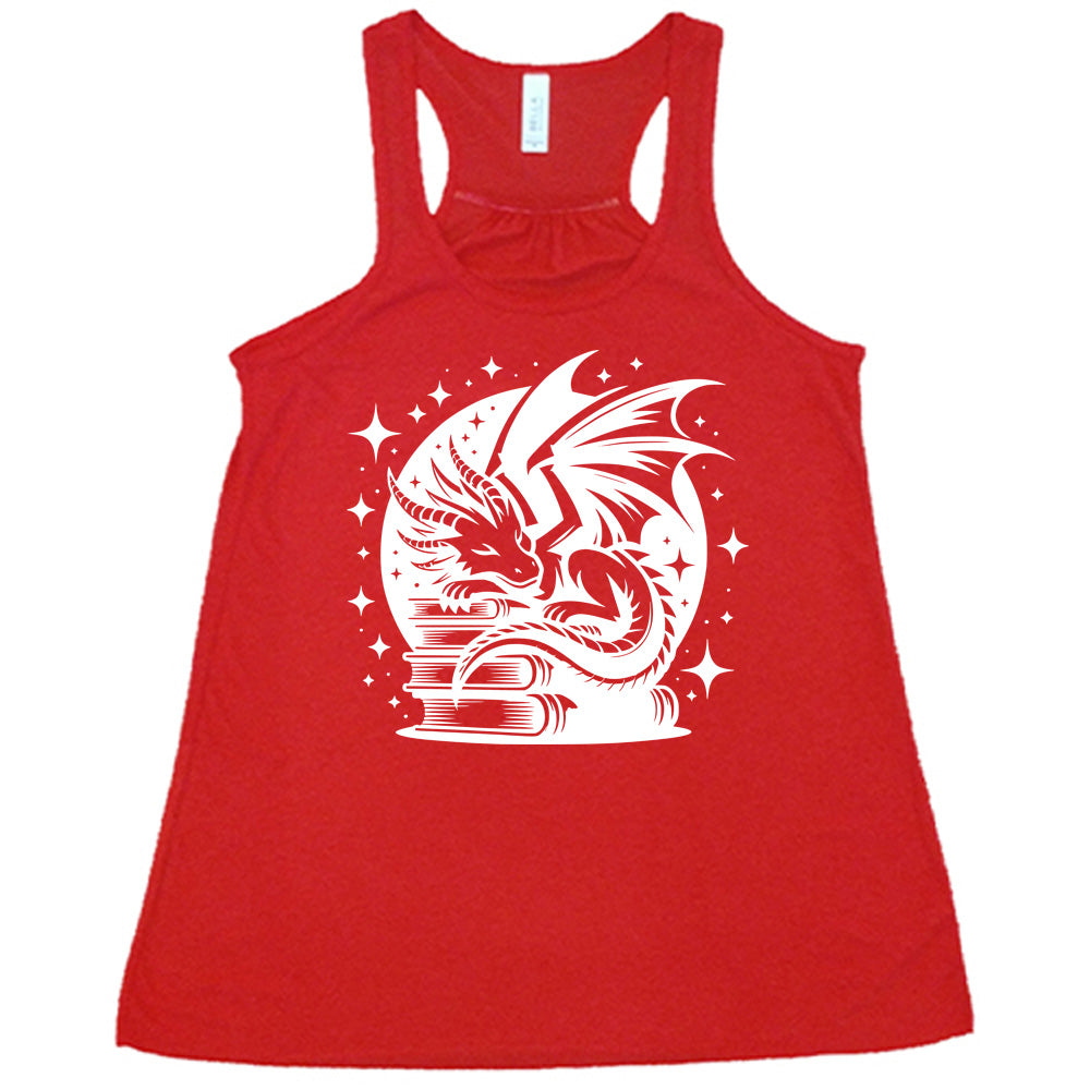 red racerback tank with the graphic of a dragon resting on a stack of books, in front of a full moon, with many stars around