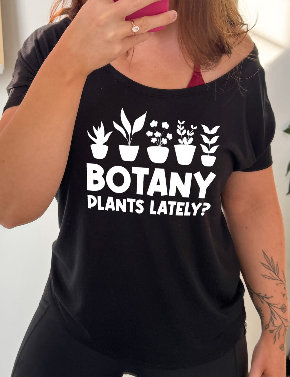 black slouchy tee with the words "Botany plants lately?" under the graphic of a line of five houseplants