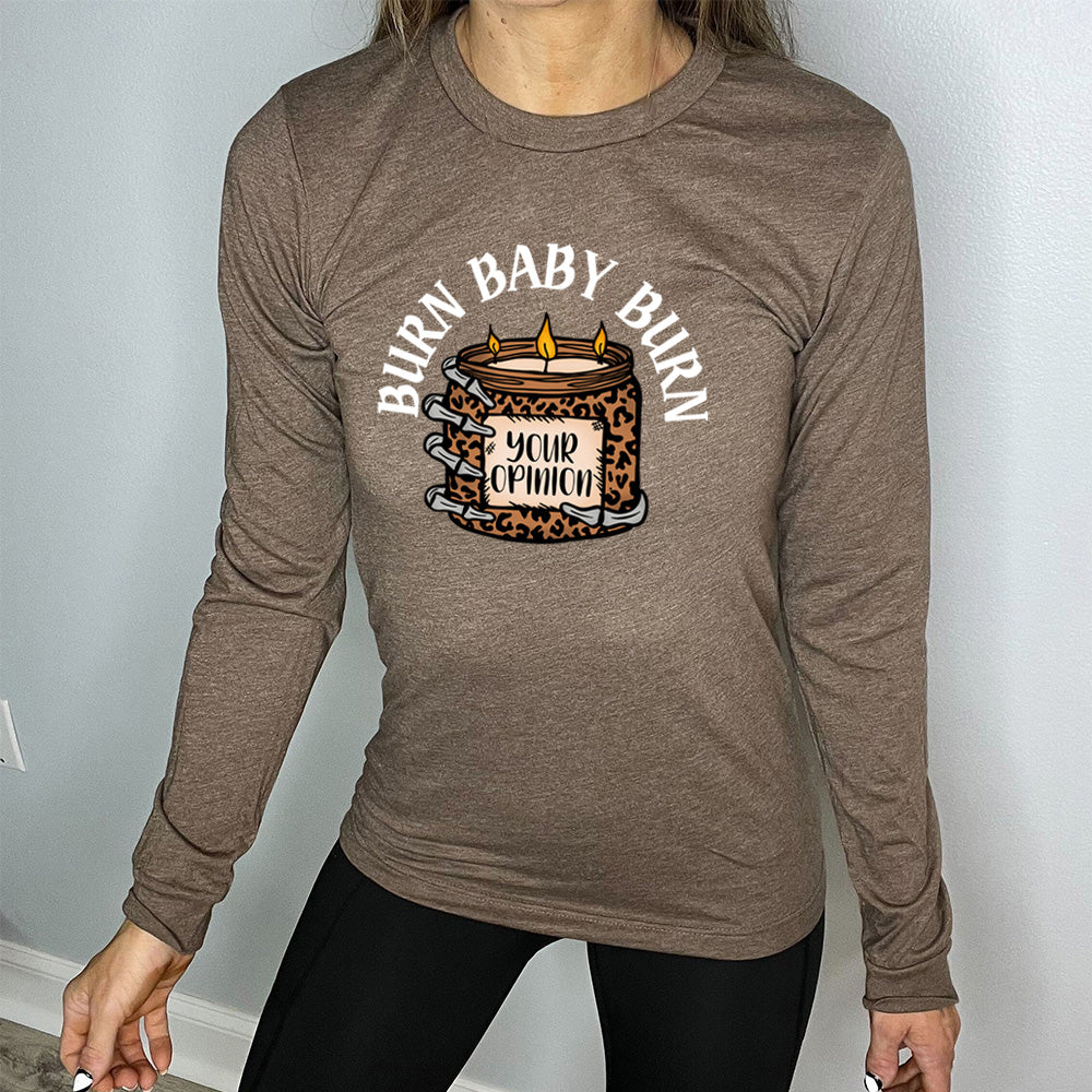 heather brown long sleeve tee with the text "Burn Baby Burn" on it, with the graphic of a skeletal hand hoping a leopard print candle, with three wicks alight, that has the words "your opinion" on it