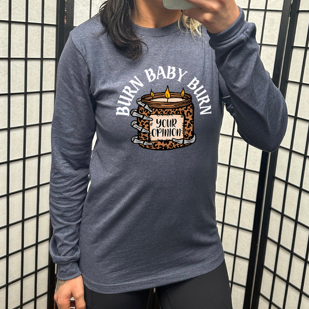 heather navy long sleeve tee with the text "Burn Baby Burn" on it, with the graphic of a skeletal hand hoping a leopard print candle, with three wicks alight, that has the words "your opinion" on it