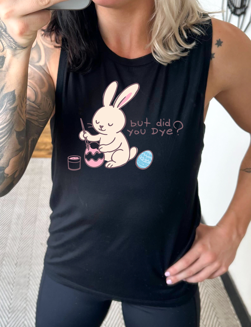 black muscle tank with the graphic of a bunny happily creating an Easter egg, with the words "but did you dye?" on it
