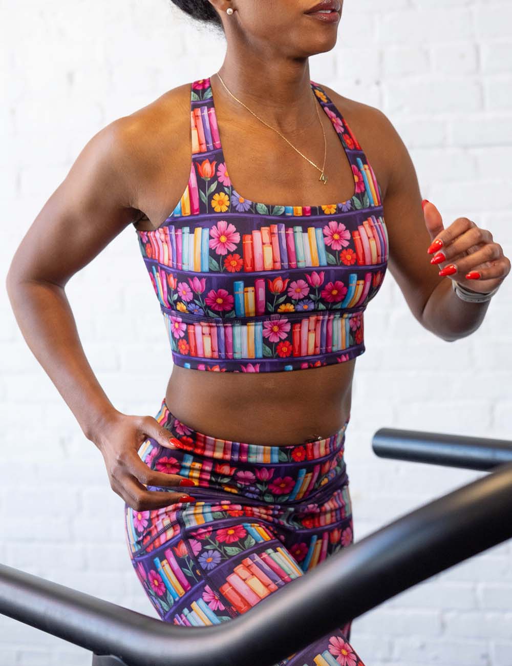 model running on a treadmill wearing a bookshelf and floral patterned workout bra and leggings