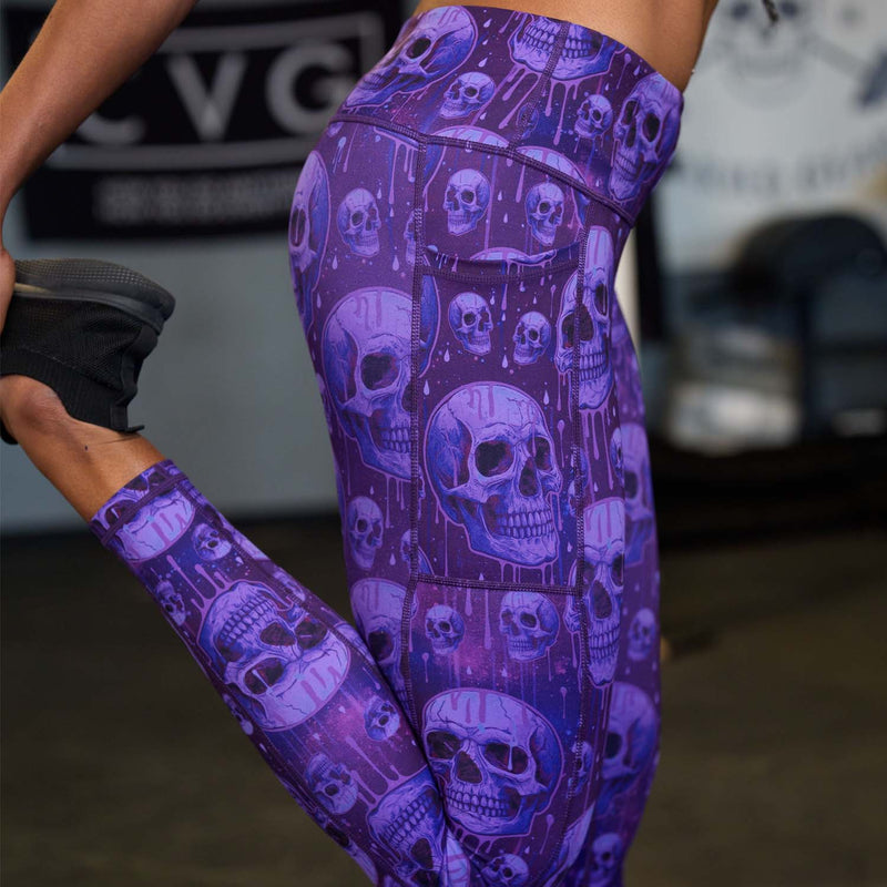 Purple leggings with skull pattern worn by a person, blurred background