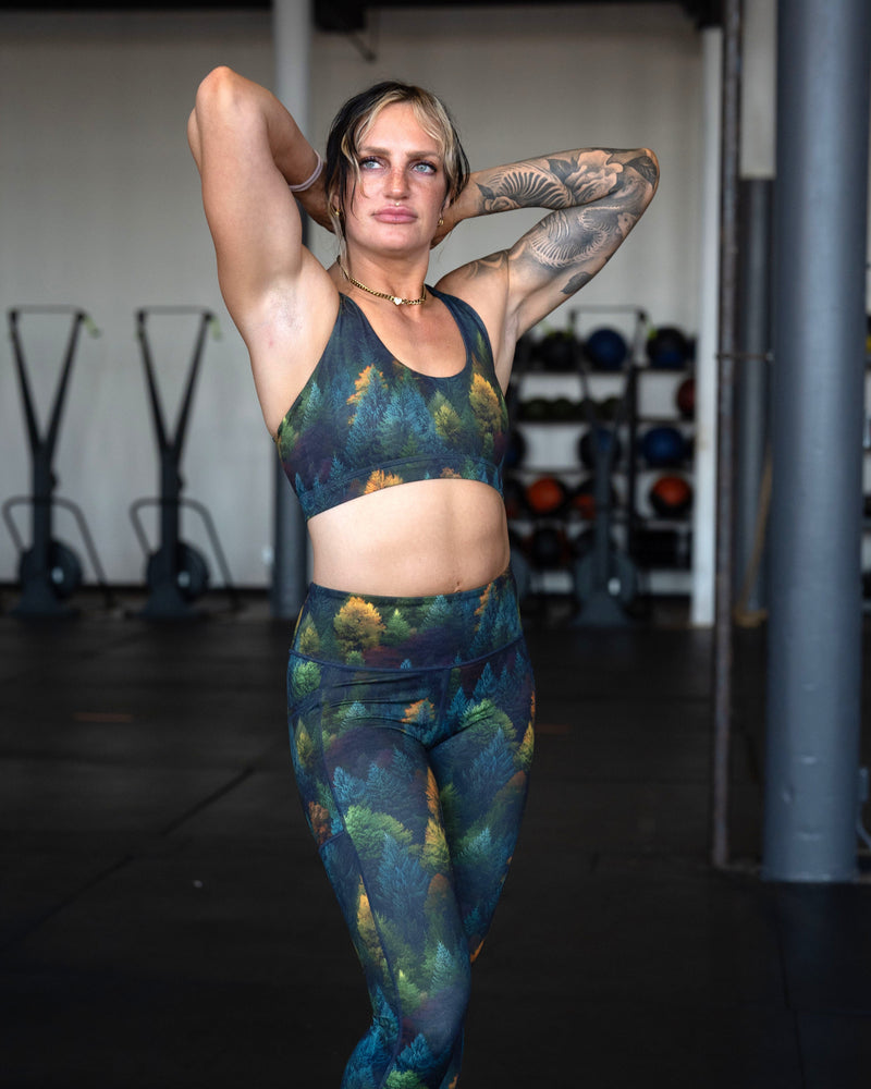 A woman posing in a gym wearing a matching sports bra and leggings set 