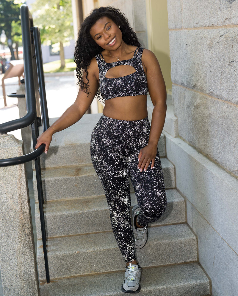 model wearing the full length black leggings with reflective spots posing on a staircase with the camera flash on