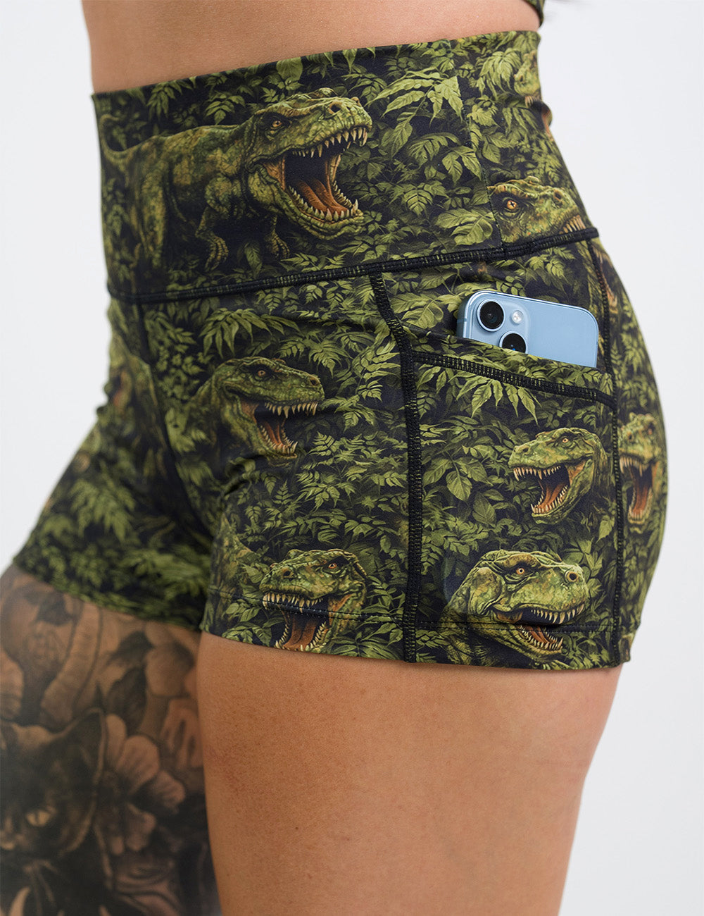 close up of the 2.5 inch t-rex in a rainforest shorts with a phone in its pocket