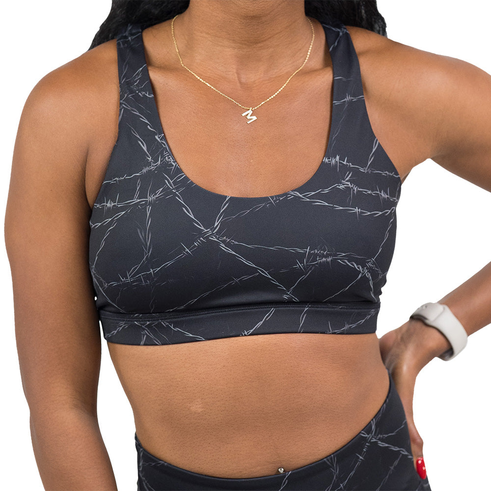 Person wearing a black sports bra with  a white barbed wire pattern on it
