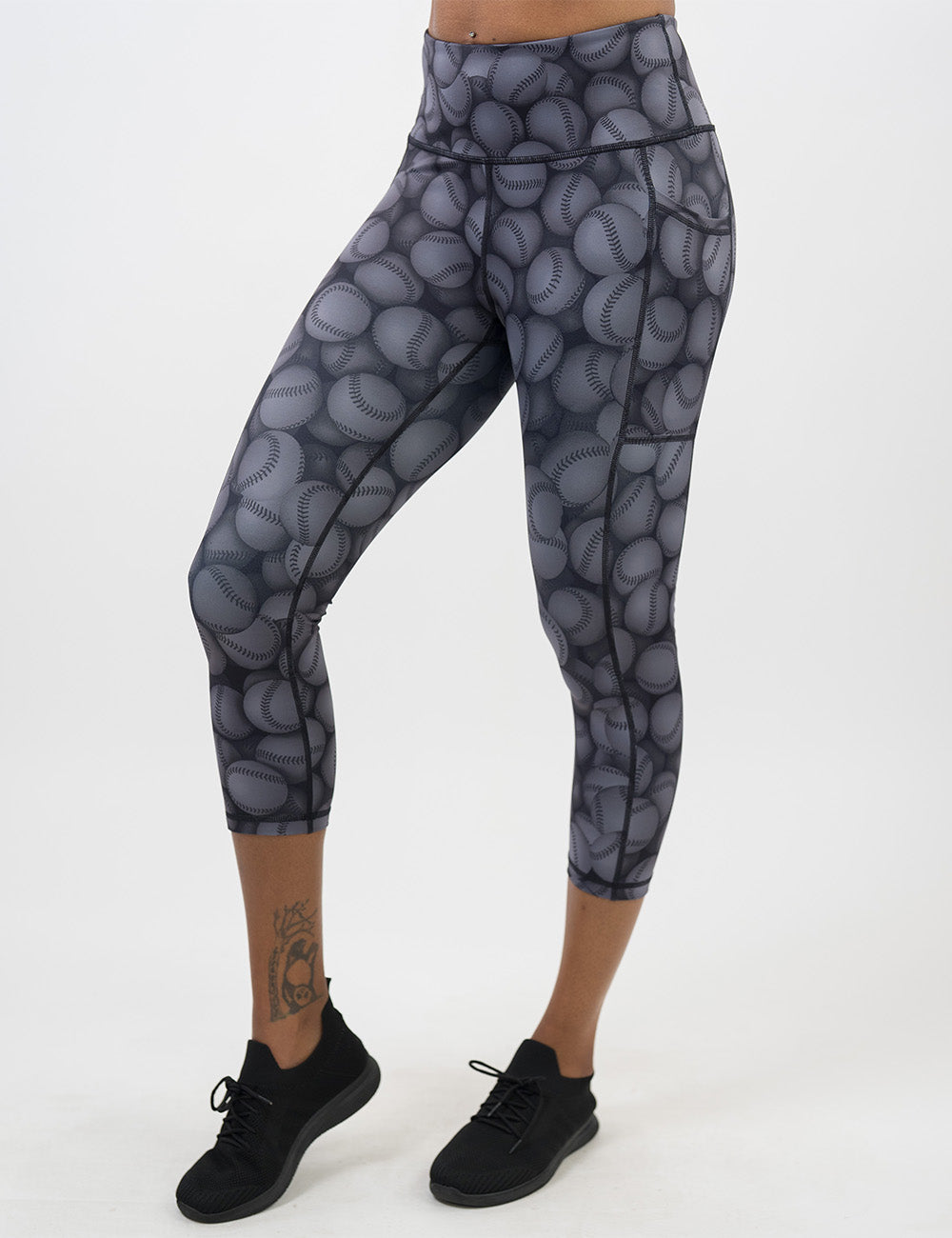 front of the dark grey baseball patterned capri leggings against a white background