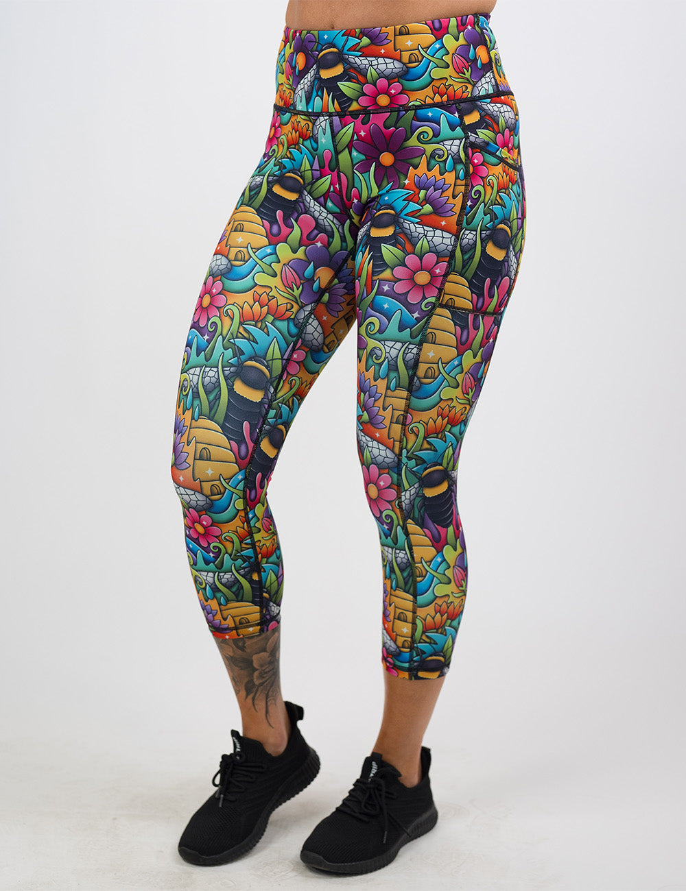 model wearing the cartoon bees against bold colorful cartoon flowers pattern capri leggings against a white background