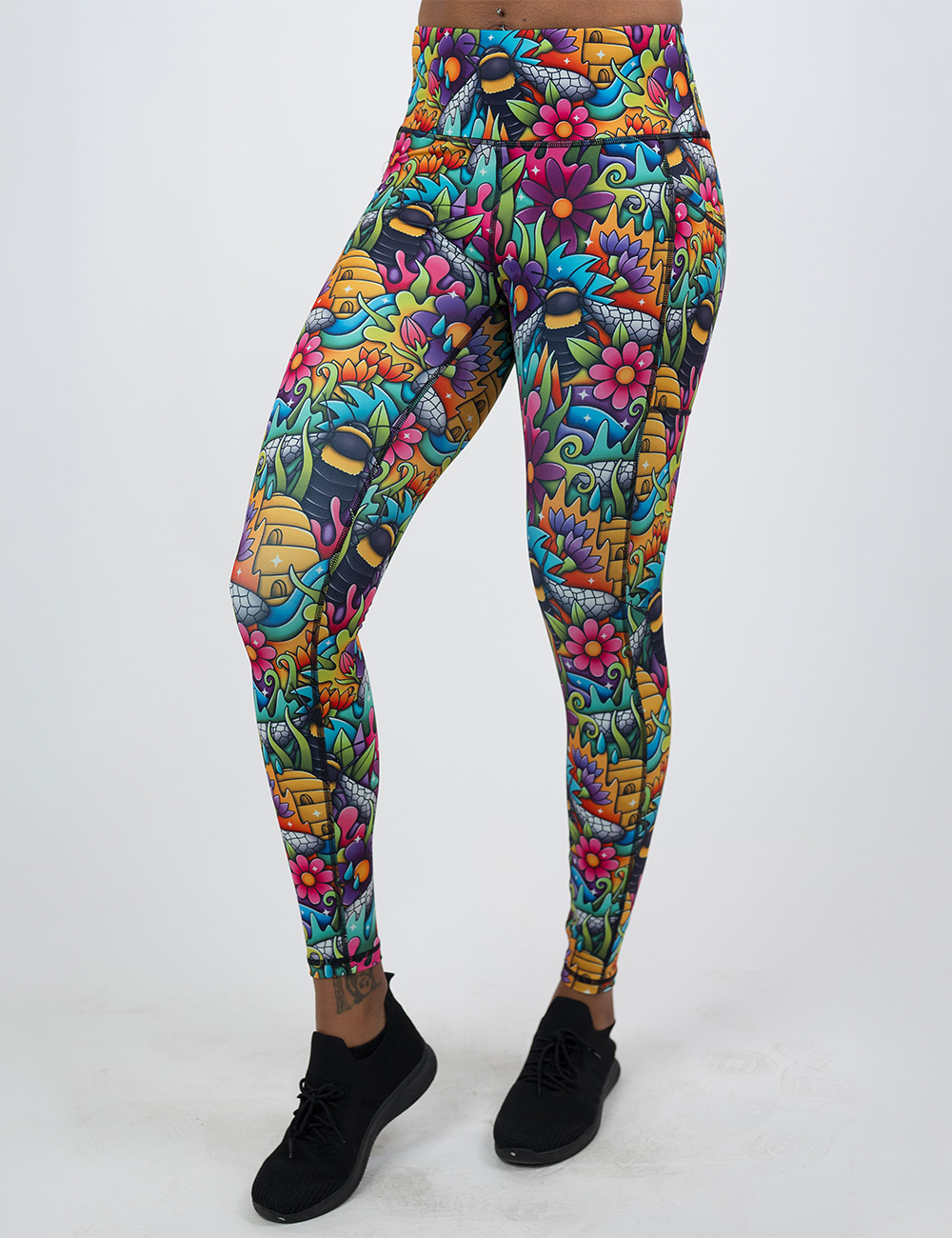model wearing the full length cartoon bees against bold colorful cartoon flowers pattern leggings against a white background
