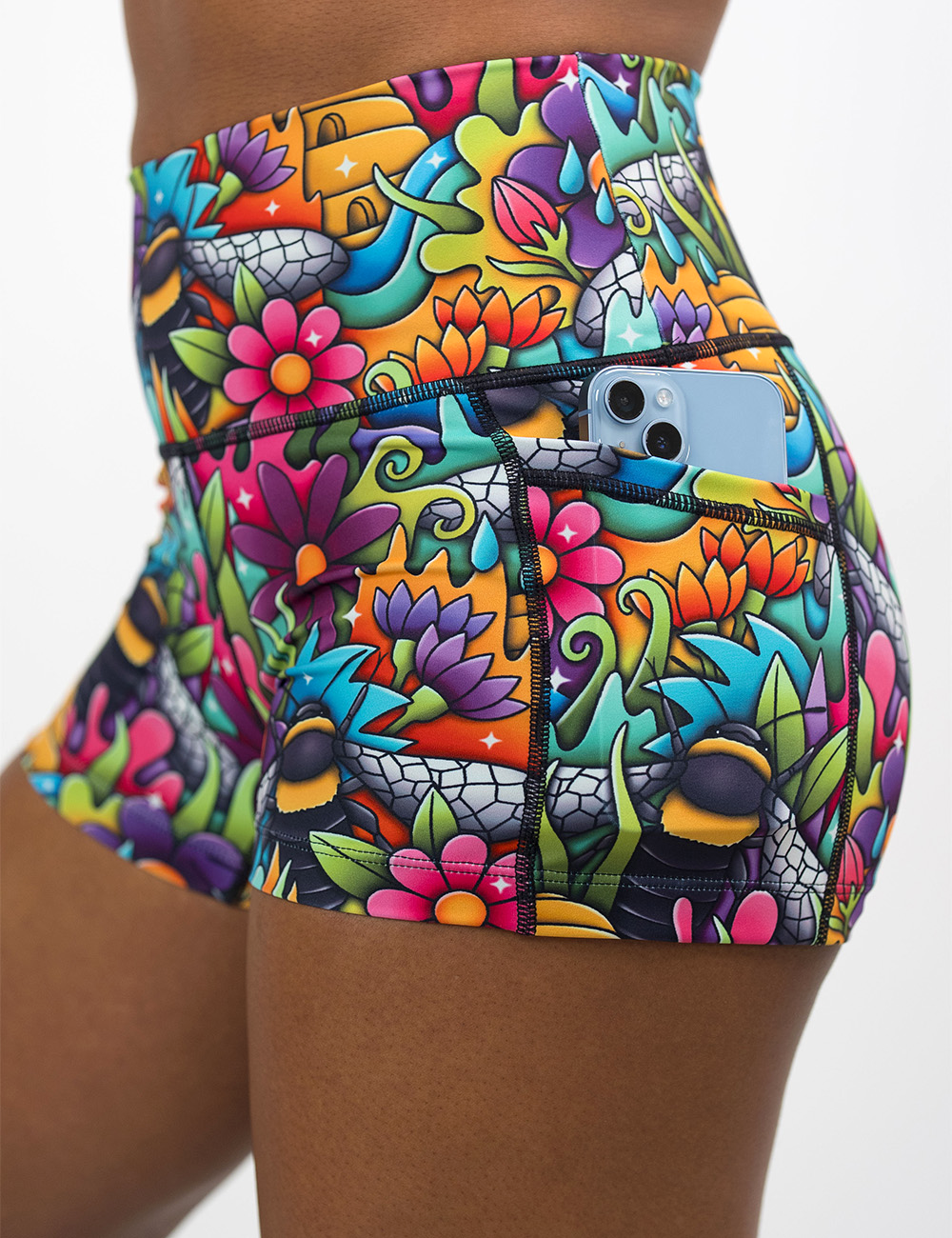 close up of the cartoon bees against colorful cartoon flowers 2.5 inch shorts with a phone in its pocket