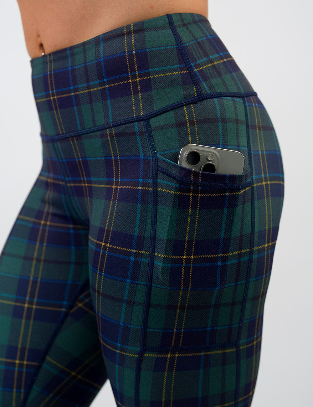 close up of the blue, green, and yellow plaid leggings with a phone in its pocket