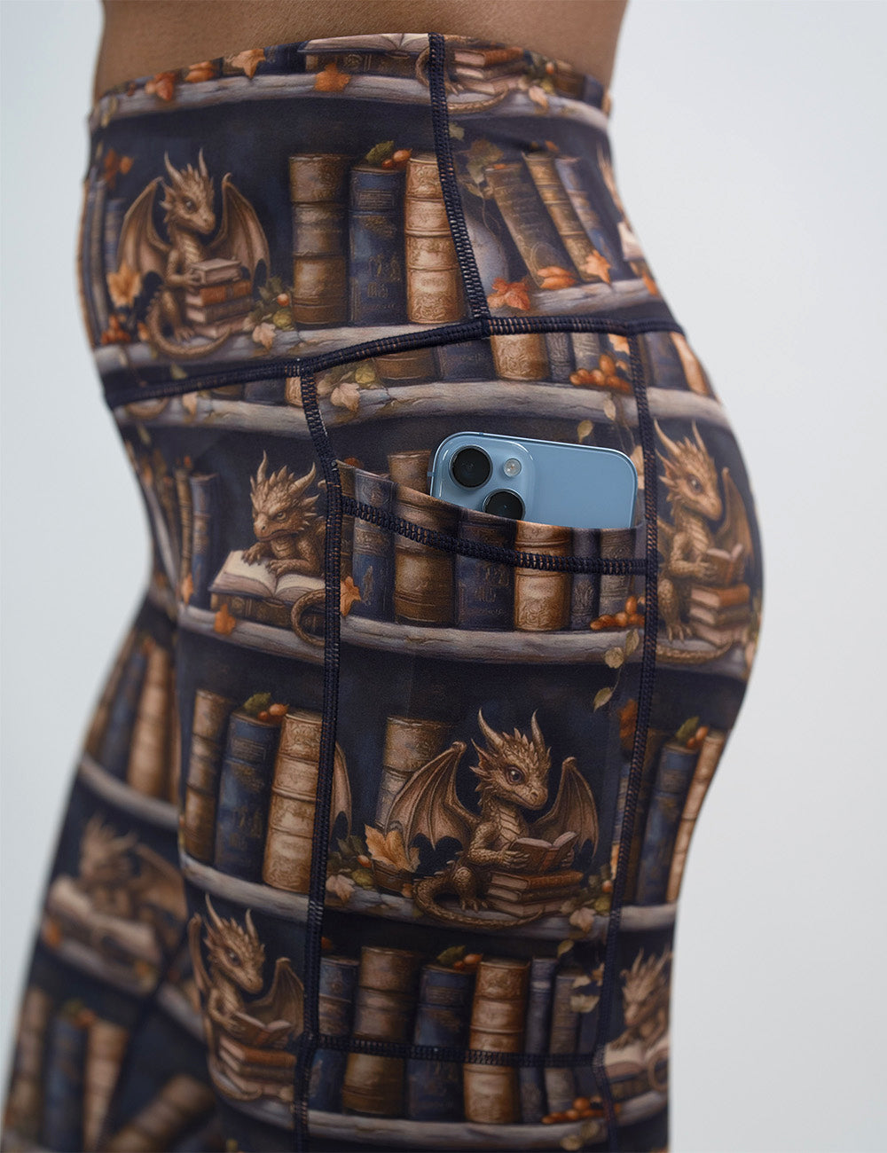 close up of the gold dragons reading books leggings with a phone in its pocket