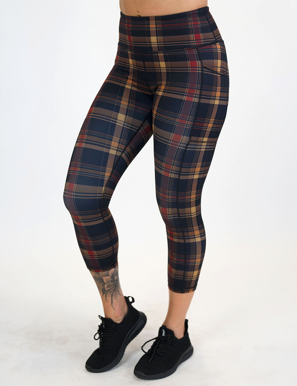 front of the red, black, and gold plaid capri leggings against a white background