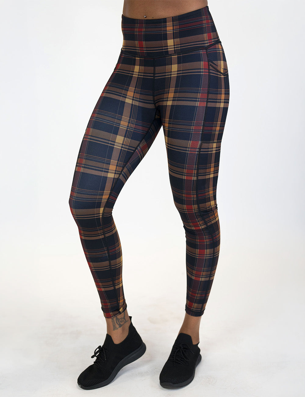front of the full length red, black, and gold plaid leggings against a white background