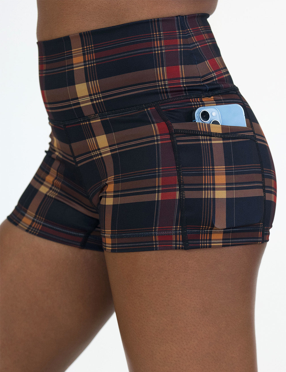 close up of the 2.5 inch black, red, and gold plaid shorts with a phone in its pocket