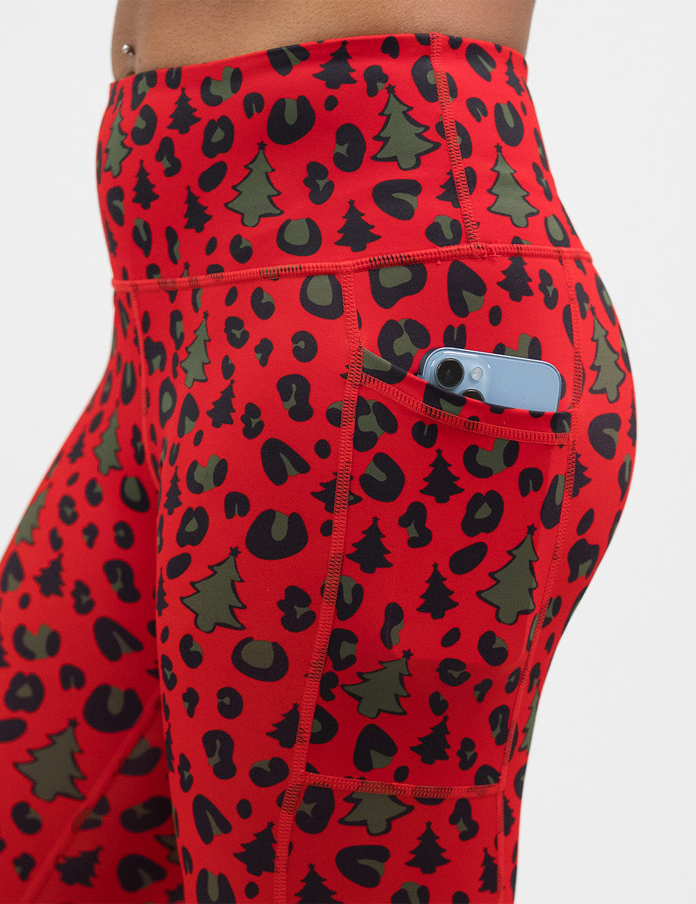 close up of the red and brown Christmas trees and leopard print leggings with a phone in its pocket