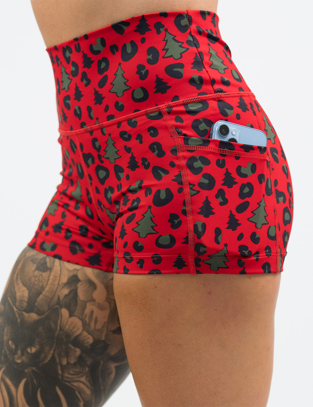 front of the red and brown Christmas trees and leopard print 2.5 inch shorts with a phone in its pocket
