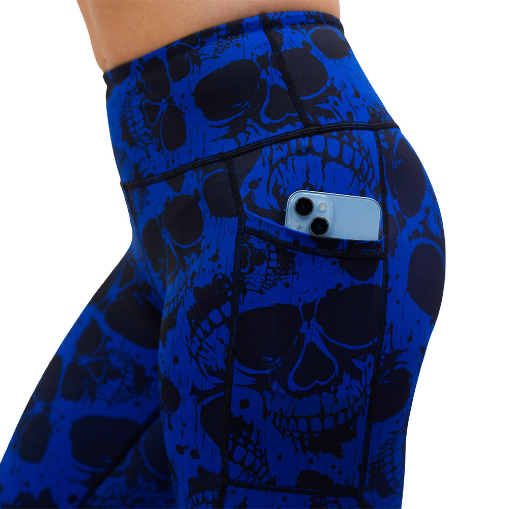 close up of the dark skulls against a blue background pattern leggings with a phone in the pocket