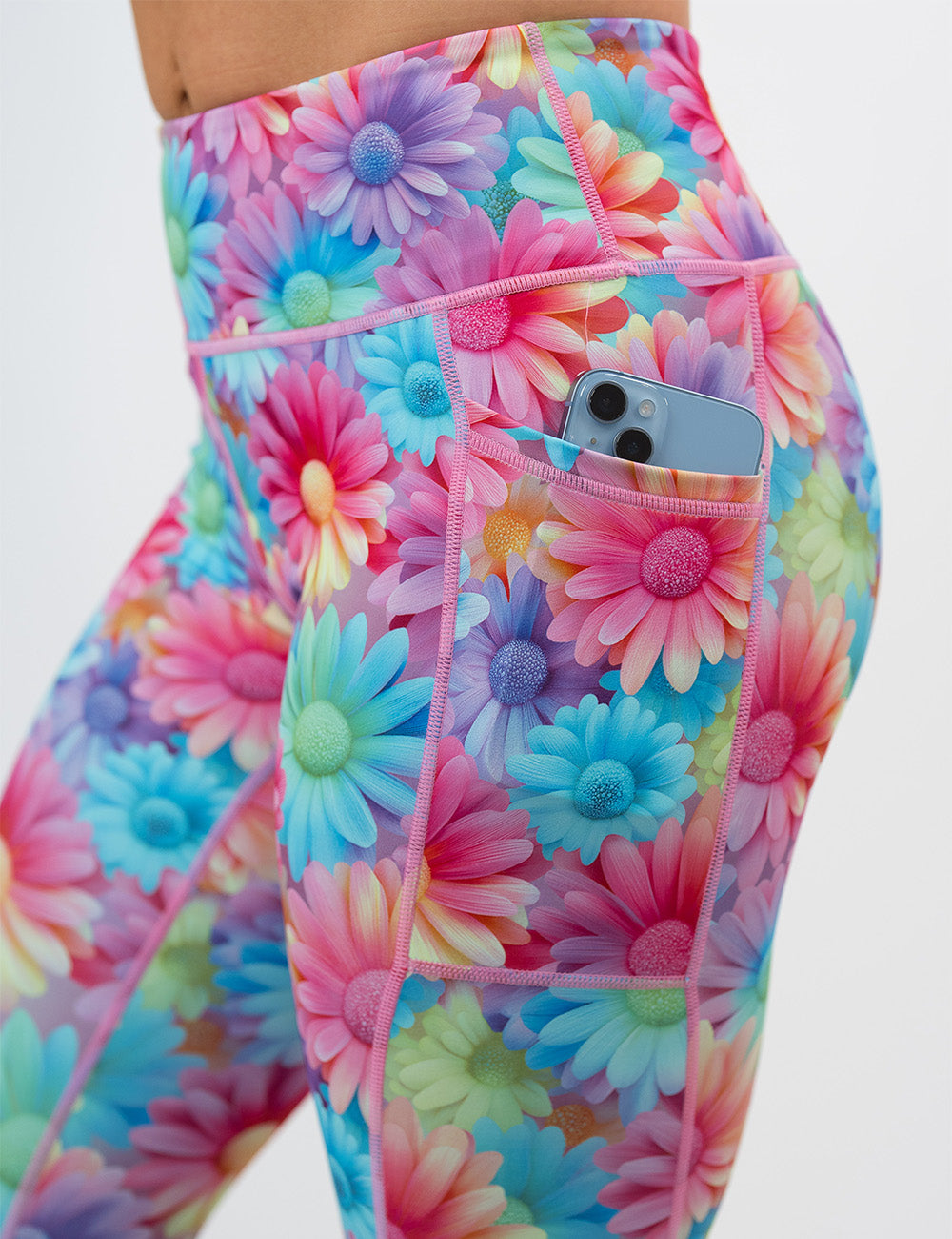 close up of the colorful flower pattern leggings pocket with a phone inside against a white background
