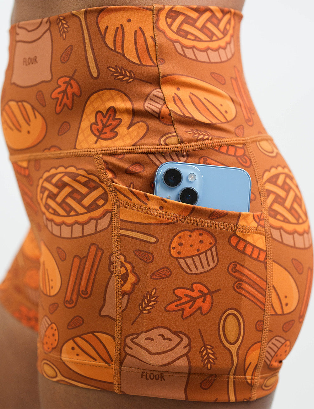 close up of the orange baking themed shorts with a phone in its pocket