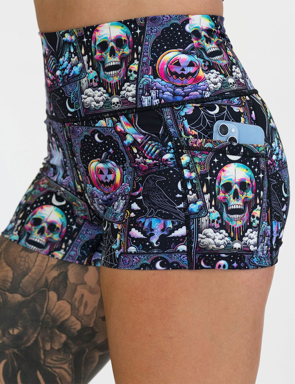 close up of the rainbow skulls, jack o lantern, and ghosts 2.5 inch shorts with a phone in its pocket