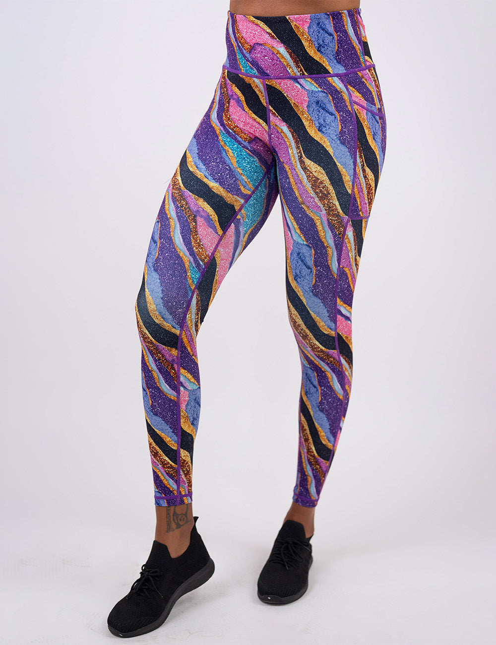 front of the purple, gold, black, blue, and pink abstract stripes full length leggings against a white background