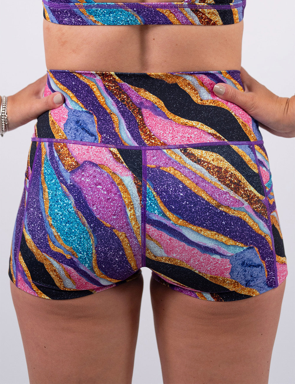 back of the 2.5 inch purple, gold, black, blue, and pink abstract stripes shorts against a white background
