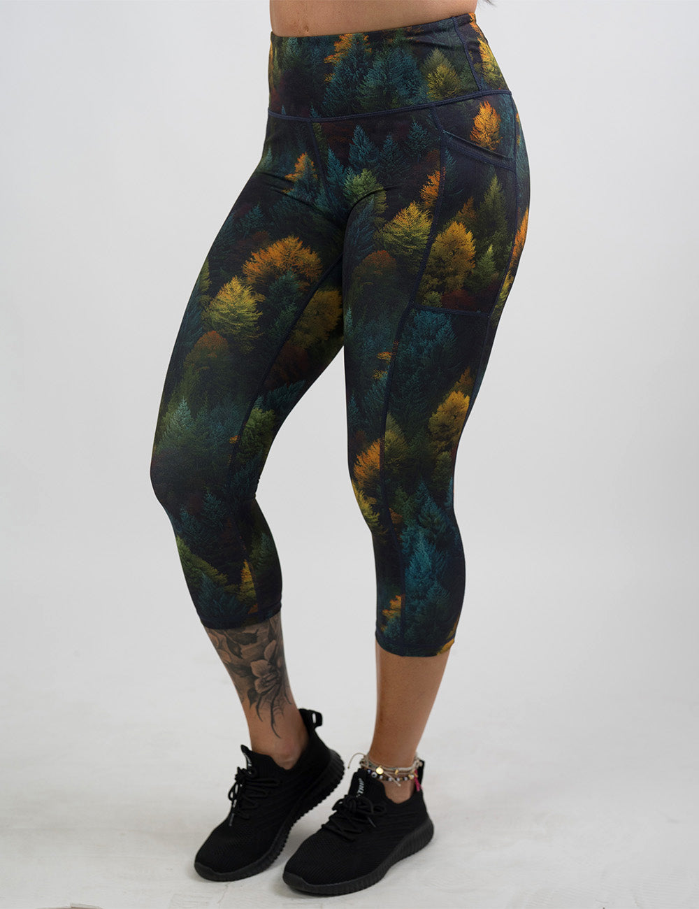 front of the orange, green, and bluish green trees capri leggings against a white background