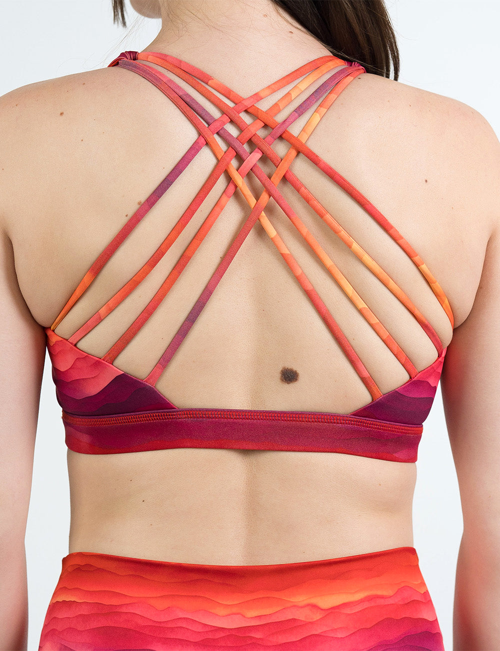 back of the red, orange, and yellow sunset stripes pattern butterfly back bra against a white background