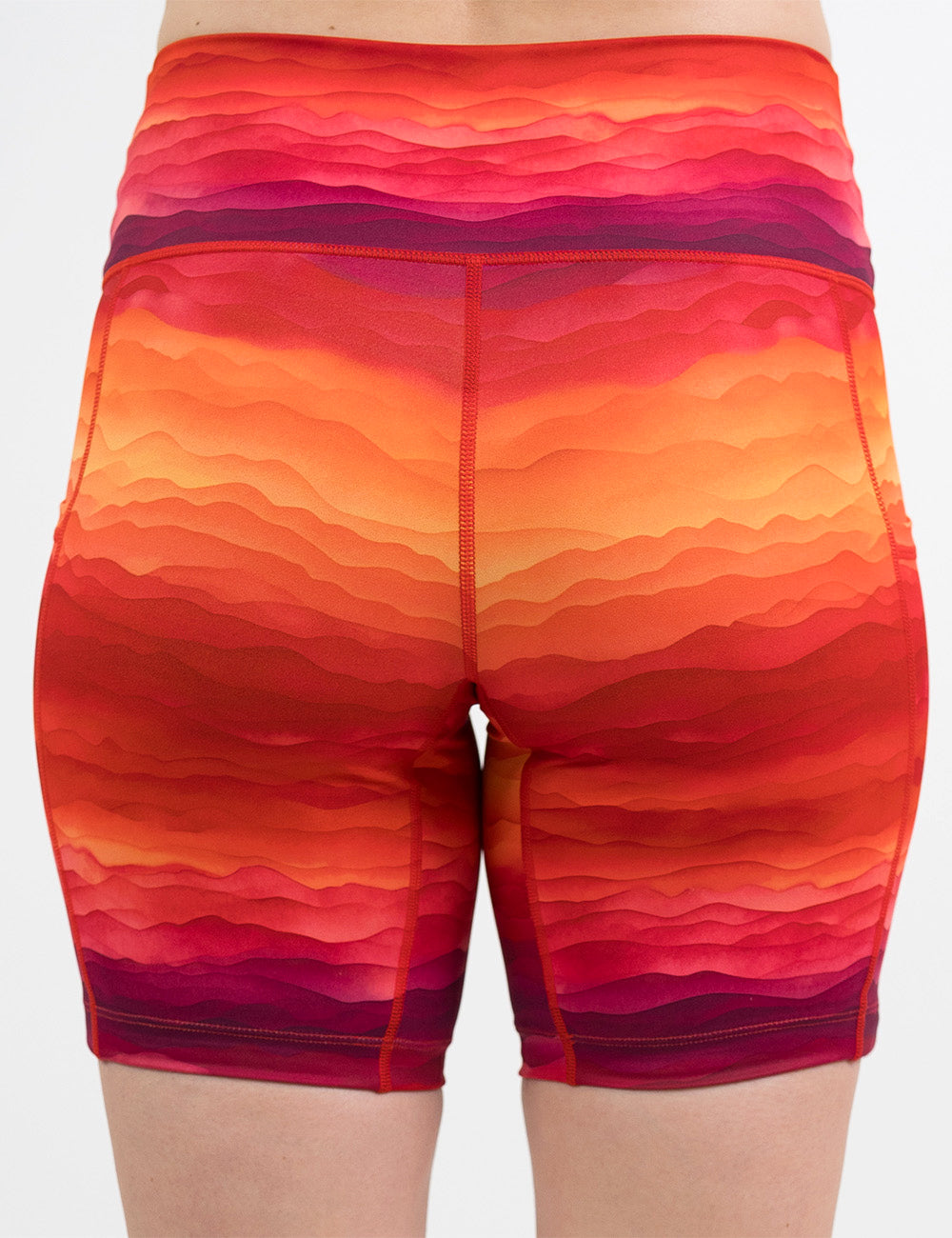 back of the 7 inch red, yellow, and orange sunset stripes pattern shorts against a white background