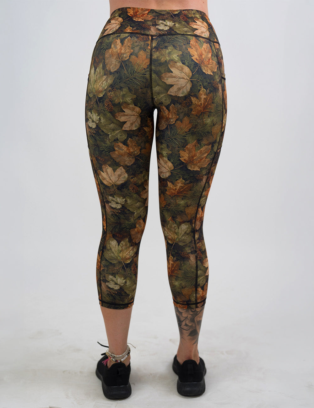 back of the forest floor covered in leaves capri leggings against a white background