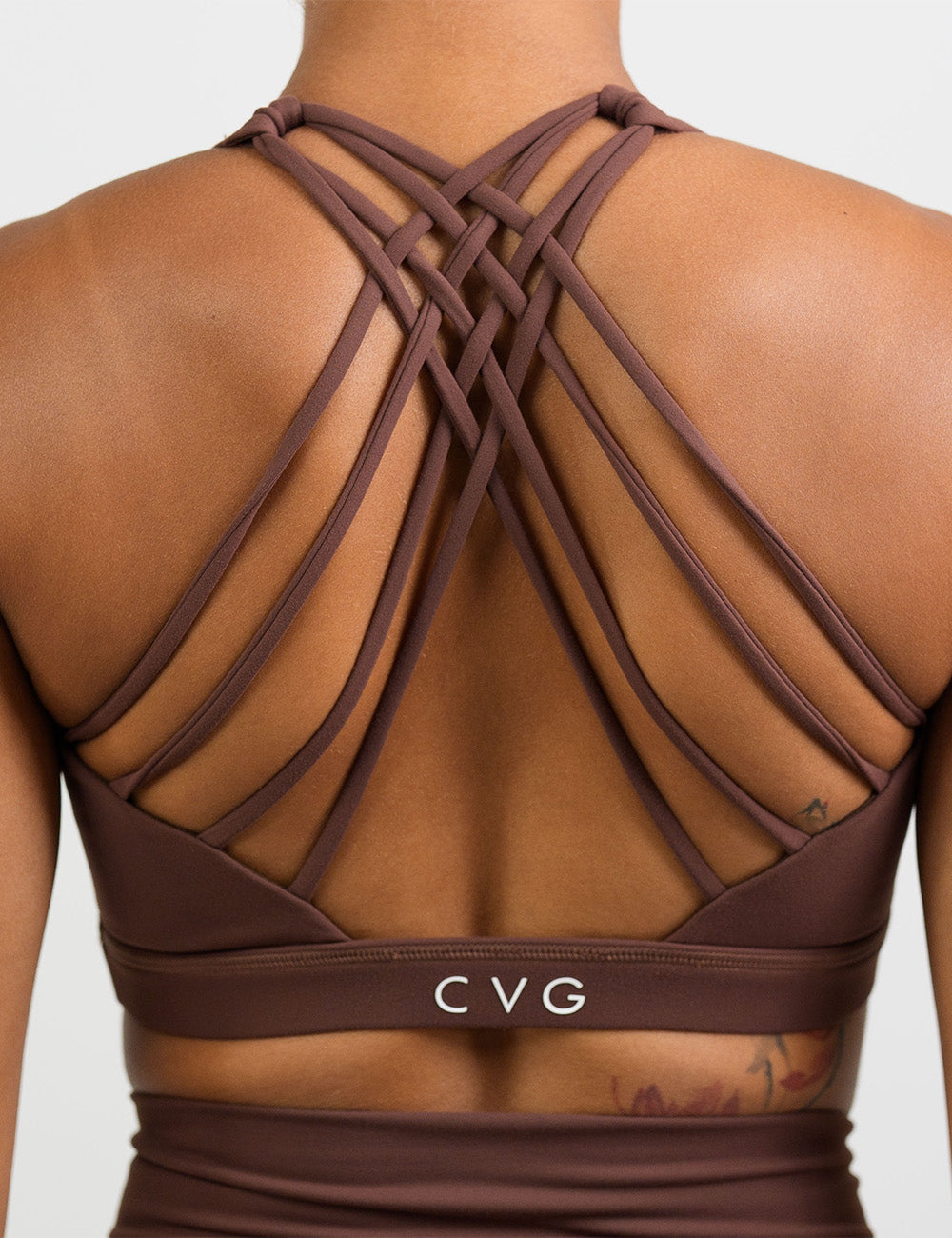 back of the solid light brown sports bra against a white background