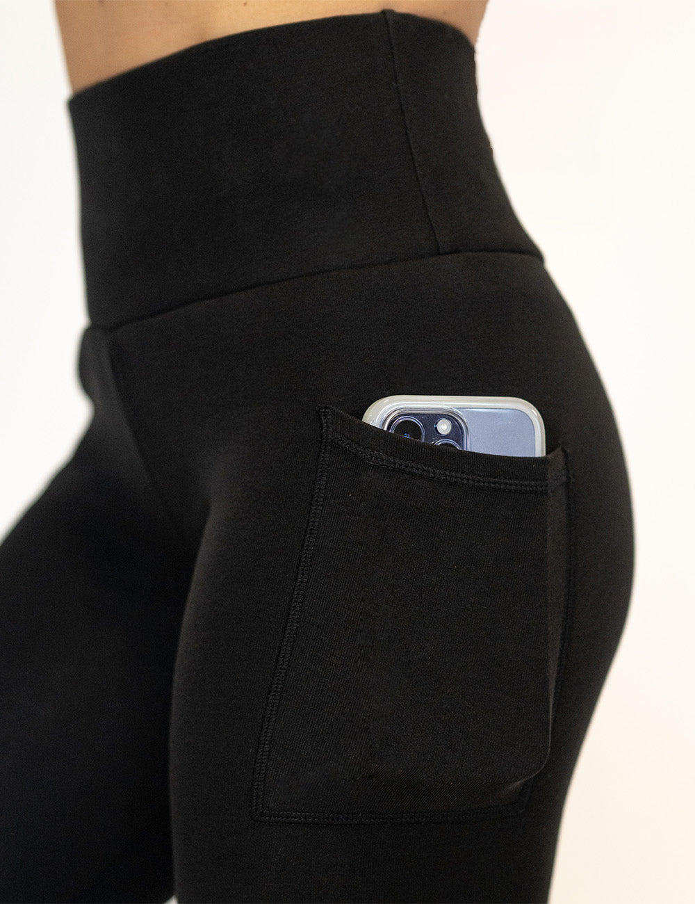 close up of the solid black fleece lined leggings with a phone in its pocket