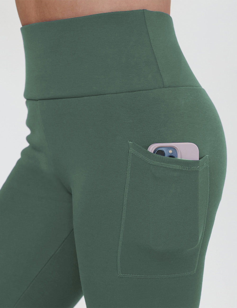 close up of the dark green fleece lined leggings with a phone in its pocket